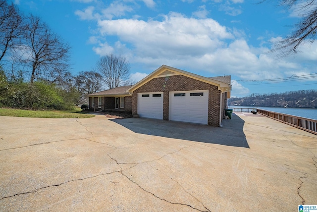 view of front of house featuring brick siding, driveway, a garage, and a water view