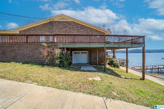 view of front facade featuring a front lawn, brick siding, a water view, and driveway