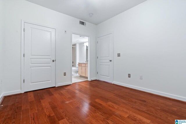 401 20th St S Unit 309, Birmingham, AL 35233 - unfurnished bedroom featuring visible vents, connected bathroom, baseboards, and wood finished floors