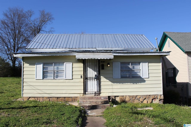 bungalow-style home featuring a front lawn and metal roof