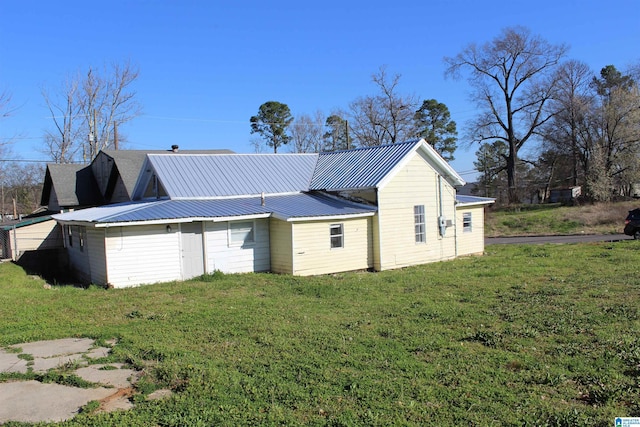 view of property exterior featuring metal roof and a lawn