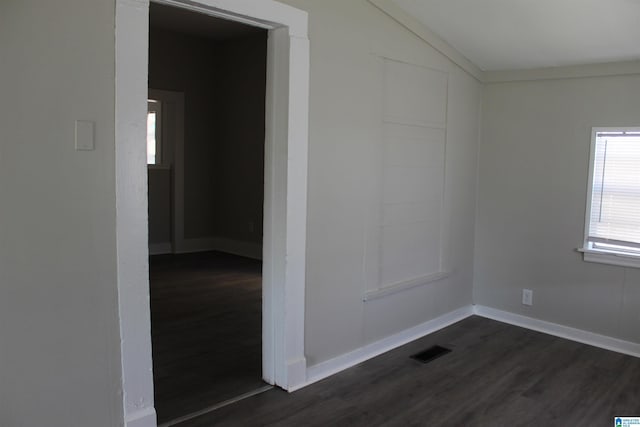 spare room with dark wood finished floors, vaulted ceiling, baseboards, and visible vents