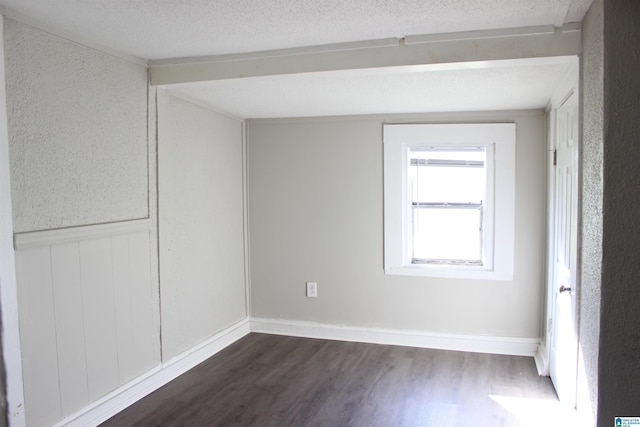 unfurnished room featuring dark wood-type flooring, wainscoting, and a textured ceiling