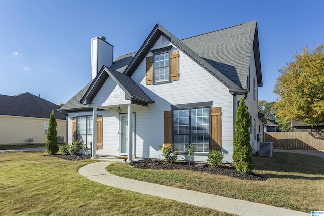 view of front facade with roof with shingles, a chimney, a front lawn, and fence