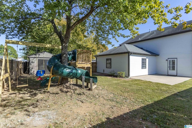 view of yard featuring a playground, a shed, a fenced backyard, an outbuilding, and a patio