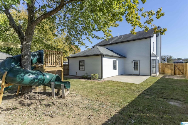 back of house featuring a patio, a lawn, a playground, and fence