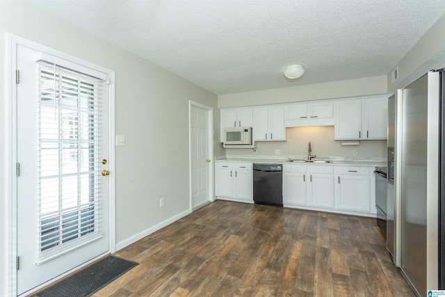 kitchen with white microwave, a sink, light countertops, stainless steel refrigerator with ice dispenser, and dishwasher