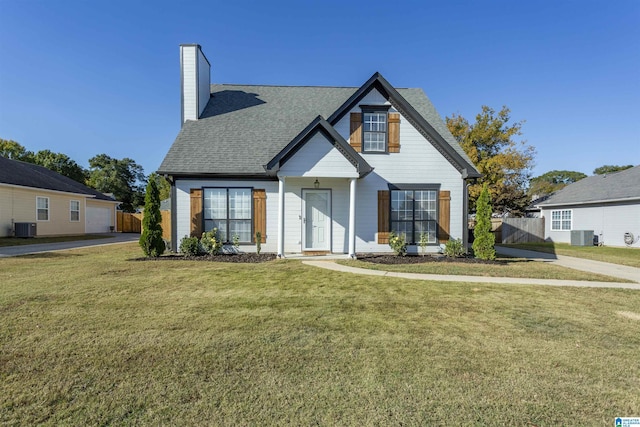 view of front of home featuring a front lawn, cooling unit, fence, and a shingled roof