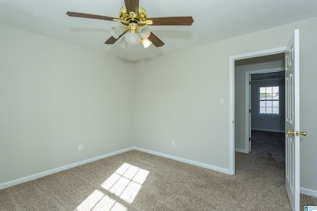 empty room with carpet flooring, ceiling fan, a textured ceiling, and baseboards