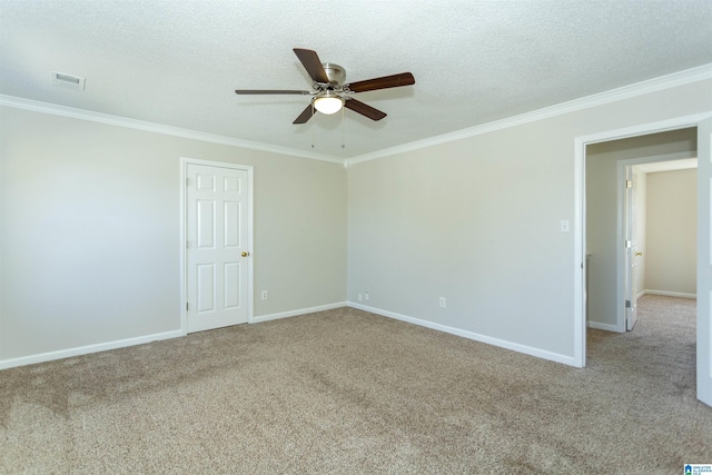 carpeted spare room featuring baseboards, visible vents, ceiling fan, a textured ceiling, and crown molding