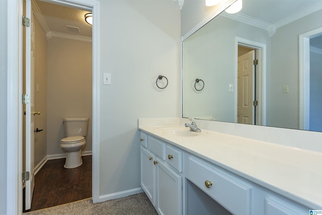 bathroom with vanity, toilet, baseboards, and ornamental molding