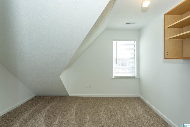 additional living space with baseboards, carpet floors, and a textured ceiling