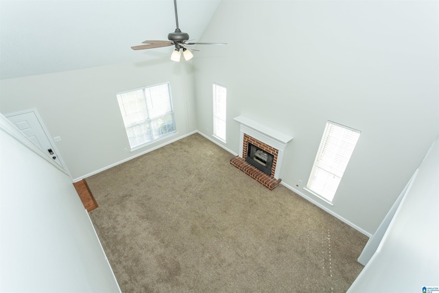 unfurnished living room featuring high vaulted ceiling, a ceiling fan, carpet flooring, baseboards, and a brick fireplace