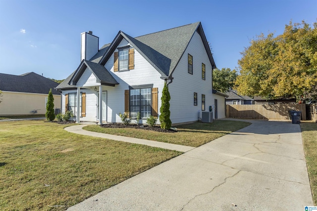 view of front of home featuring central air condition unit, driveway, fence, a front yard, and a chimney