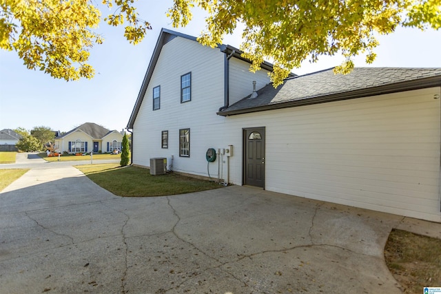 back of house featuring central AC unit and a shingled roof