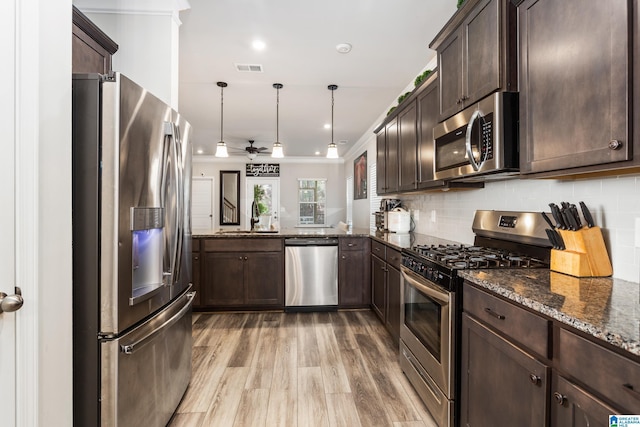 kitchen with tasteful backsplash, dark brown cabinetry, dark stone countertops, stainless steel appliances, and a sink