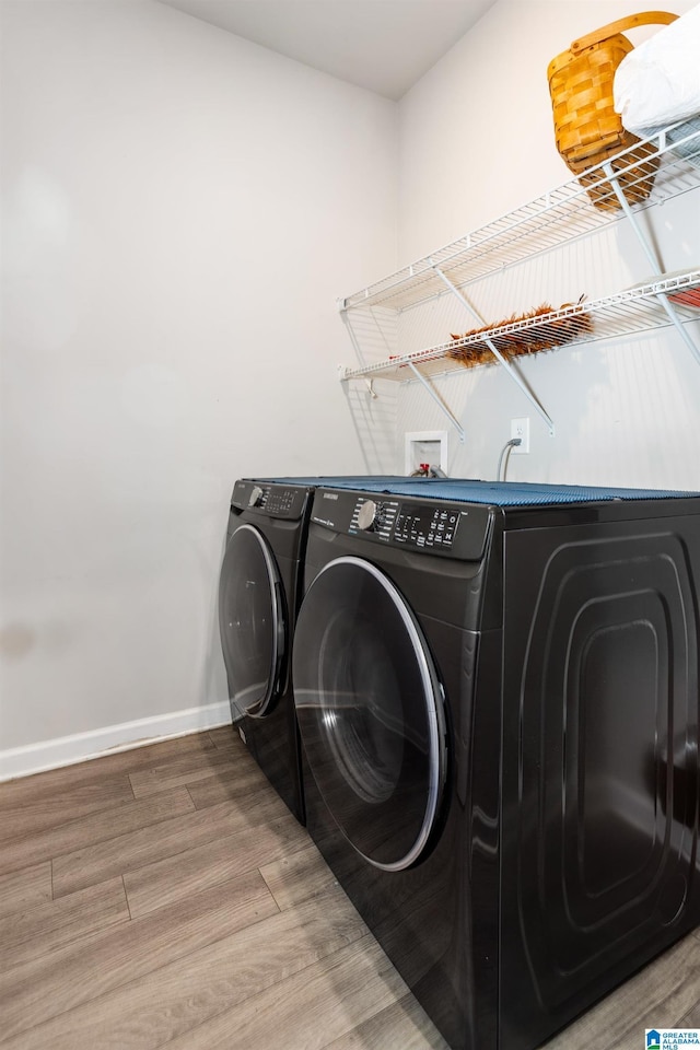 washroom featuring laundry area, washer and dryer, baseboards, and wood finished floors