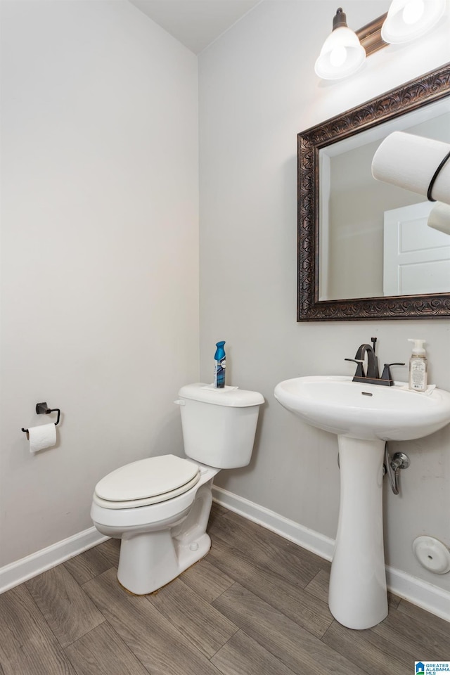 bathroom with a sink, toilet, baseboards, and wood finished floors
