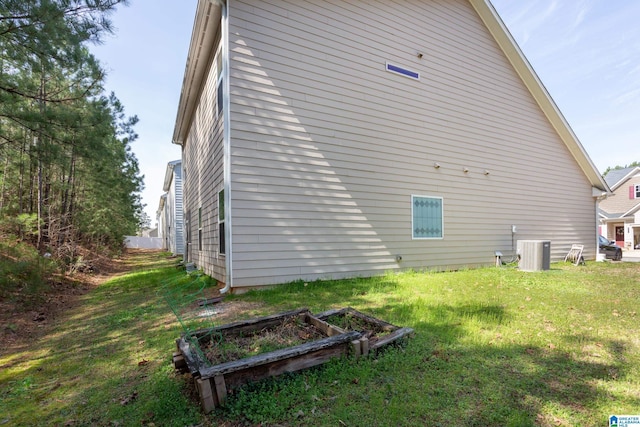 view of home's exterior with a vegetable garden, a lawn, and central AC
