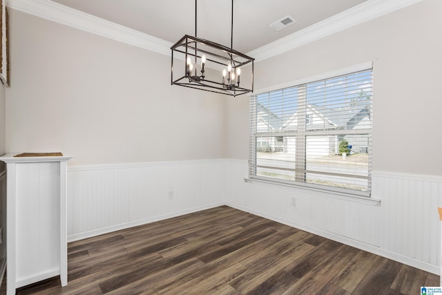 unfurnished dining area with dark wood-style floors, visible vents, wainscoting, crown molding, and a notable chandelier