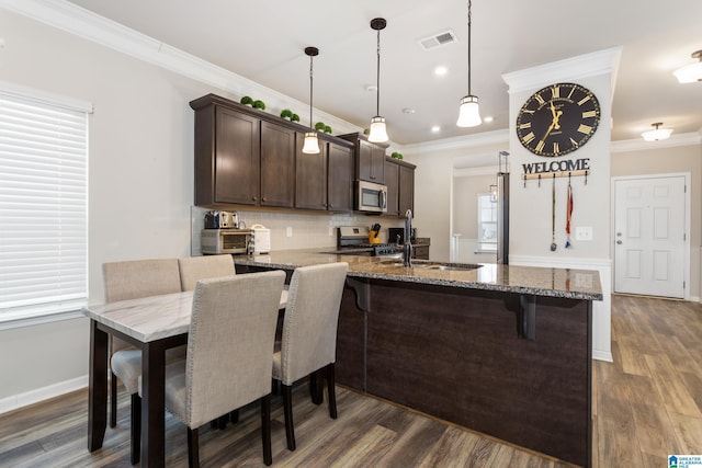 kitchen with a breakfast bar area, visible vents, a sink, dark brown cabinets, and appliances with stainless steel finishes