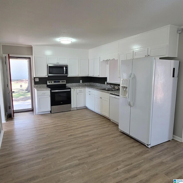 kitchen featuring light wood-style flooring, appliances with stainless steel finishes, white cabinets, a textured ceiling, and a sink