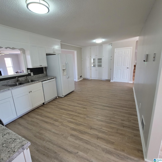 kitchen featuring white cabinets, white appliances, a textured ceiling, and a sink