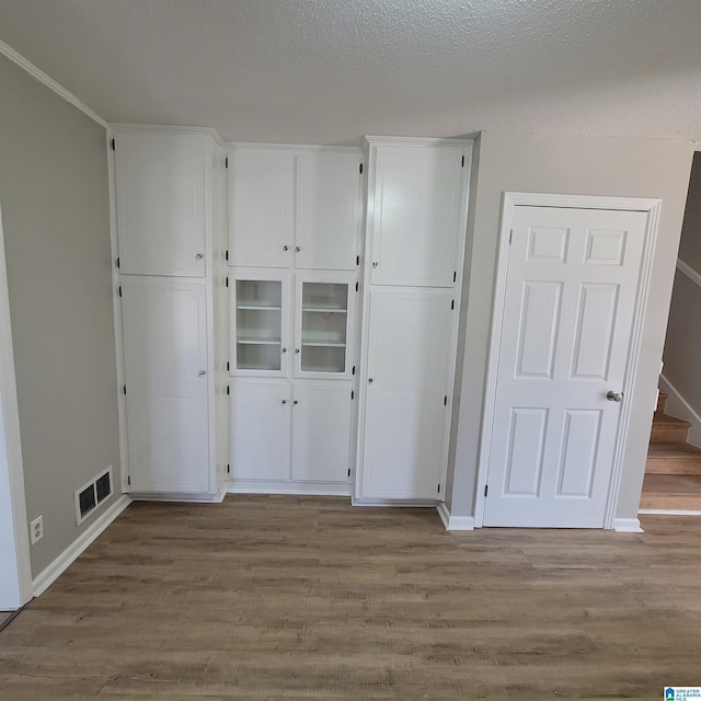 unfurnished bedroom with wood finished floors, visible vents, a closet, and baseboards