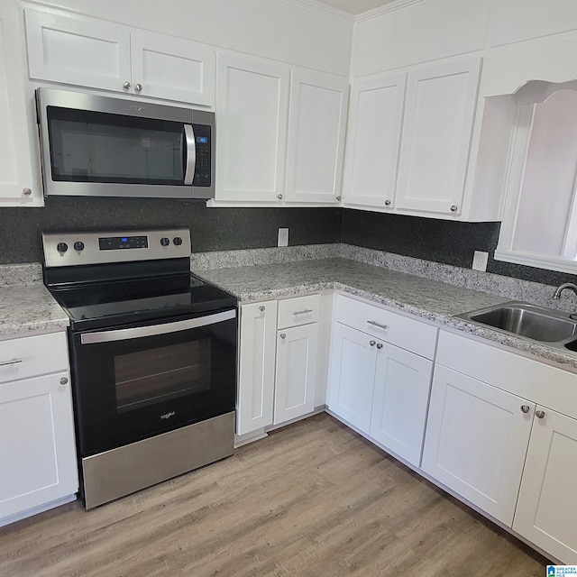 kitchen with white cabinets, light wood finished floors, appliances with stainless steel finishes, and a sink