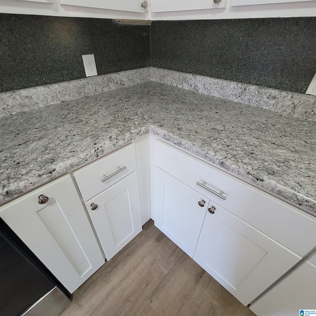 interior space with white cabinetry, wood finished floors, and light stone countertops