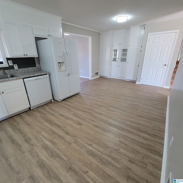 kitchen featuring light wood-type flooring, a sink, white appliances, white cabinets, and baseboards