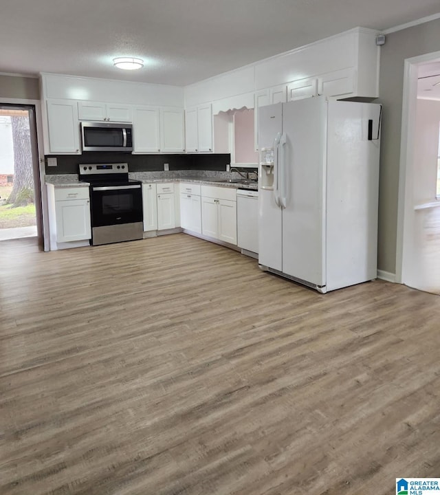 kitchen featuring white cabinets, appliances with stainless steel finishes, light wood-type flooring, and ornamental molding