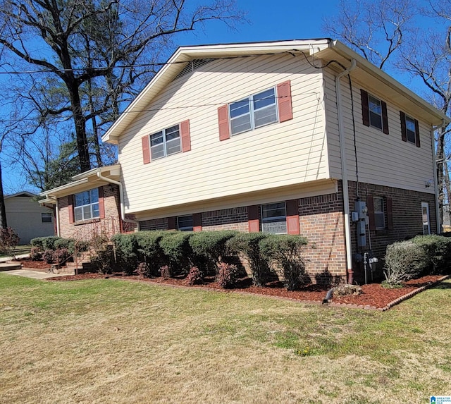 view of side of property with brick siding and a lawn