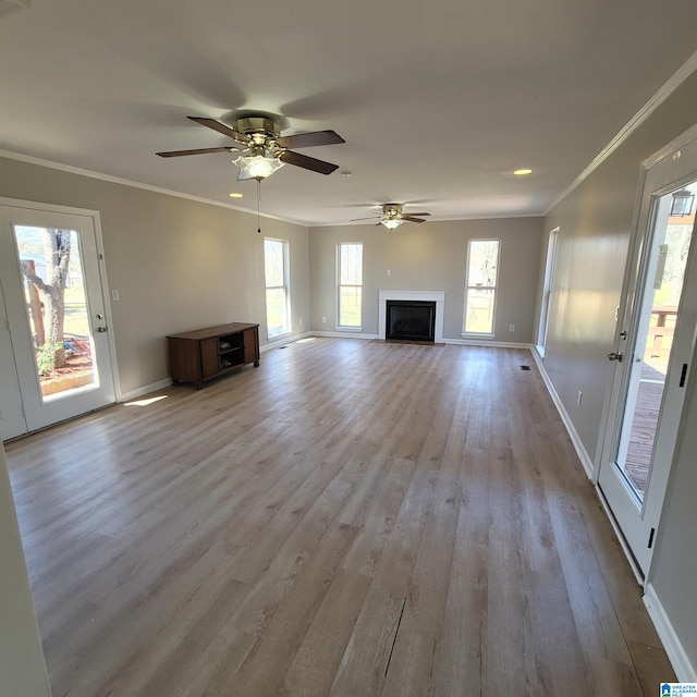 unfurnished living room with crown molding, wood finished floors, baseboards, and ceiling fan