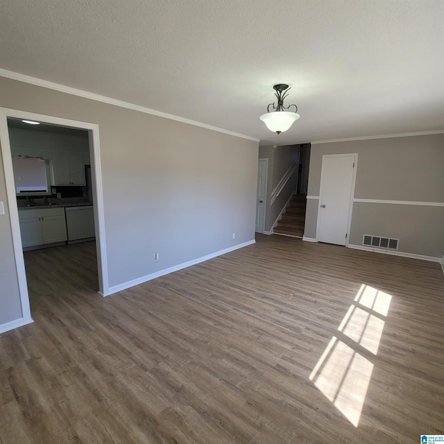 spare room featuring visible vents, crown molding, baseboards, wood finished floors, and a textured ceiling