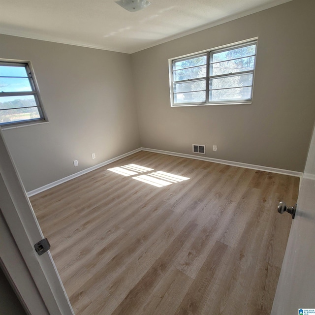 unfurnished room featuring crown molding, baseboards, visible vents, and light wood finished floors