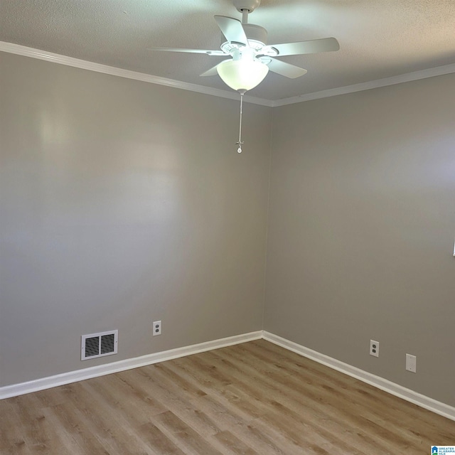 empty room with light wood-type flooring, visible vents, baseboards, and ornamental molding