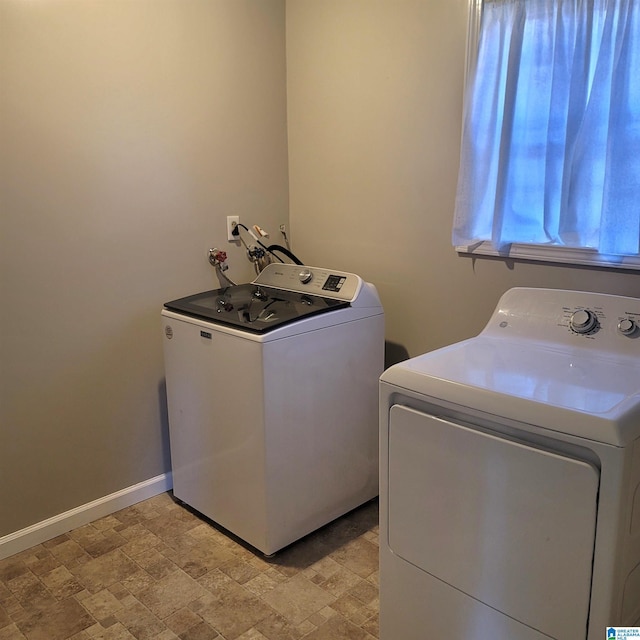 laundry room with laundry area, stone finish floor, baseboards, and separate washer and dryer