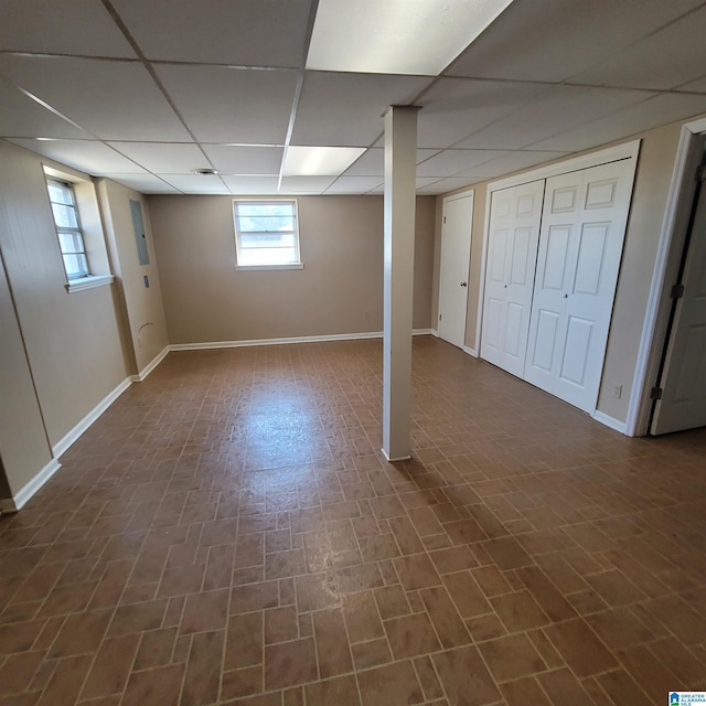 below grade area featuring baseboards and a paneled ceiling