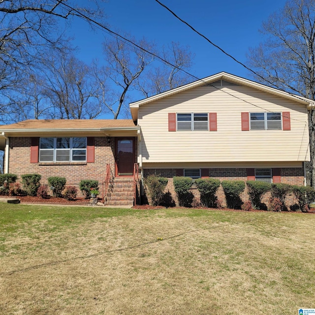 tri-level home featuring brick siding and a front yard