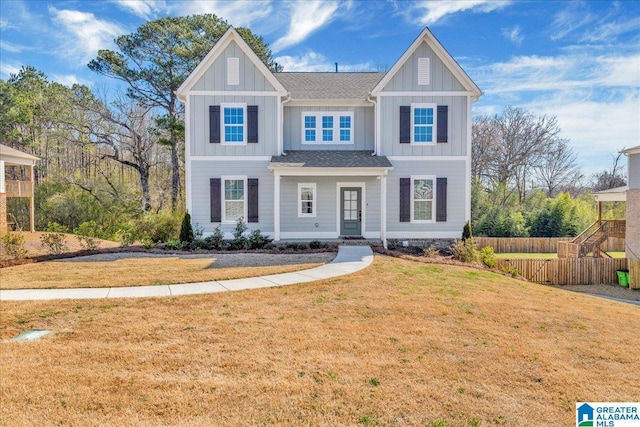 view of front of house with board and batten siding, a front yard, and fence