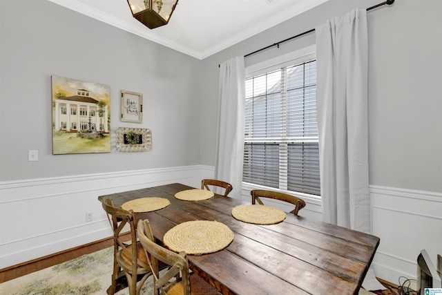 dining area with wood finished floors, a wainscoted wall, and ornamental molding