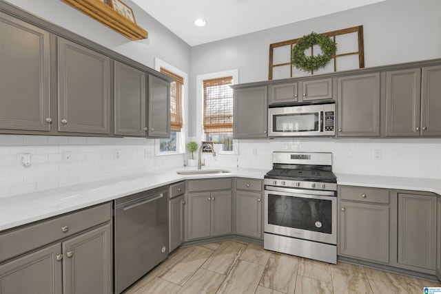 kitchen featuring a sink, stainless steel appliances, gray cabinetry, and light countertops