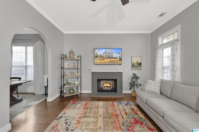 living room featuring ceiling fan, visible vents, wood finished floors, and ornamental molding