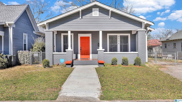 bungalow-style house with brick siding, a porch, a front yard, and fence