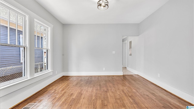 unfurnished room with wood finished floors, visible vents, and baseboards