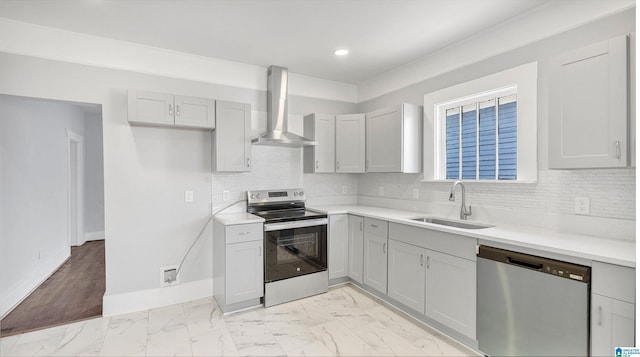 kitchen featuring baseboards, a sink, stainless steel appliances, wall chimney exhaust hood, and marble finish floor