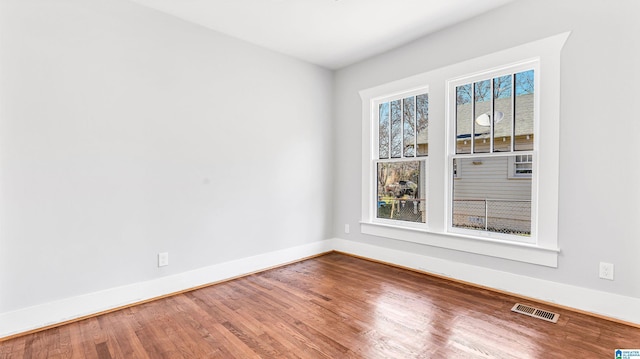 empty room with visible vents, baseboards, and wood finished floors