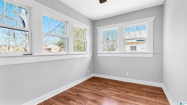 unfurnished room with baseboards, dark wood-type flooring, and ceiling fan