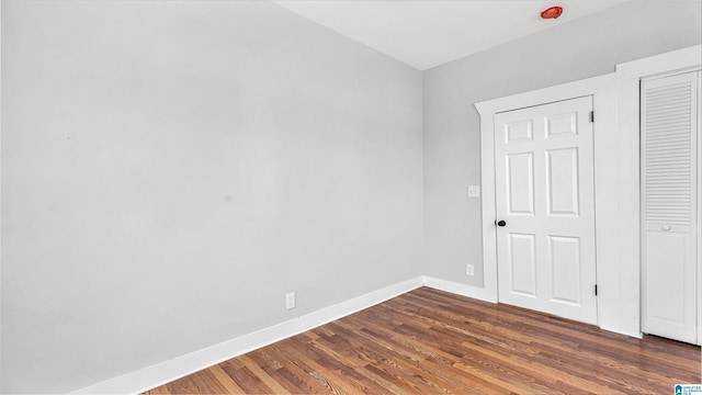 unfurnished bedroom featuring a closet, baseboards, and dark wood-style flooring